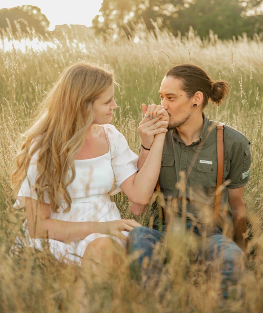 An engaged couple sitting in the fields of golden hour light at Fort Vancouver in Vancouver, WA